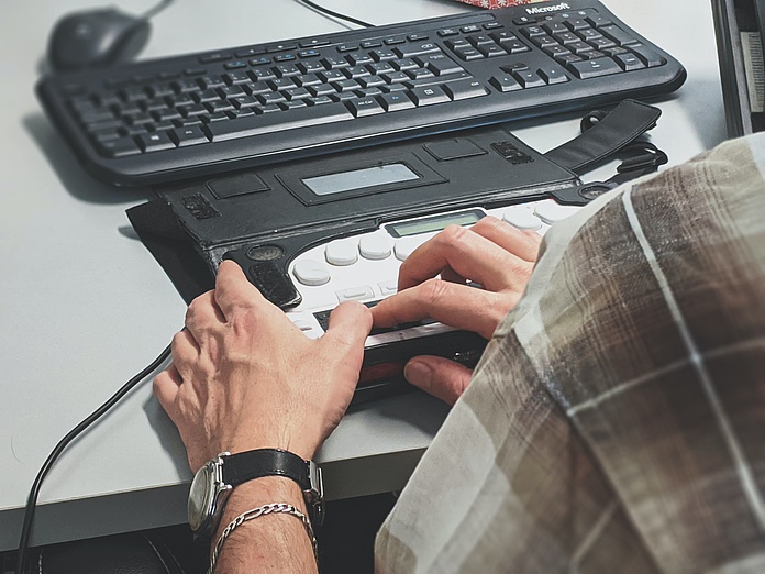 Ein Mann bedient eine Tastatur und noch ein weiteres elektronisches Gerät