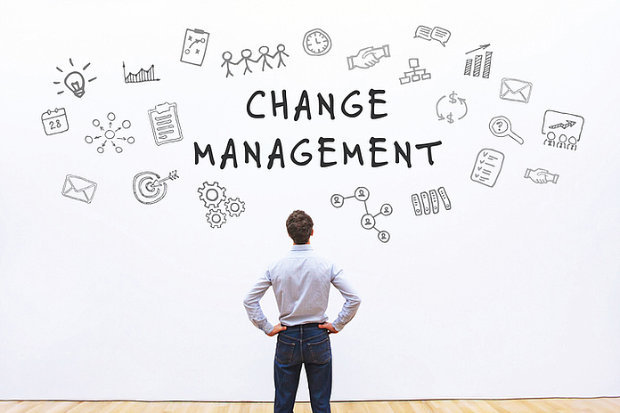 Ein Mann steht vor der Tafel und blickt auf eine Change Management Darstellung darauf.