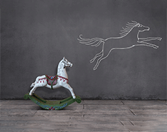 Ein Schaukelpferd und ein Pferd auf der dahinterliegenden Kreidewand gezeichnet.
