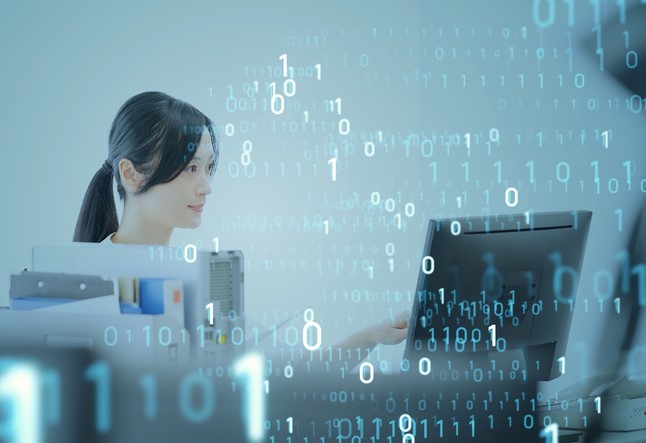 Eine Frau sitzt am Laptop hinter einem digitalen Schleier