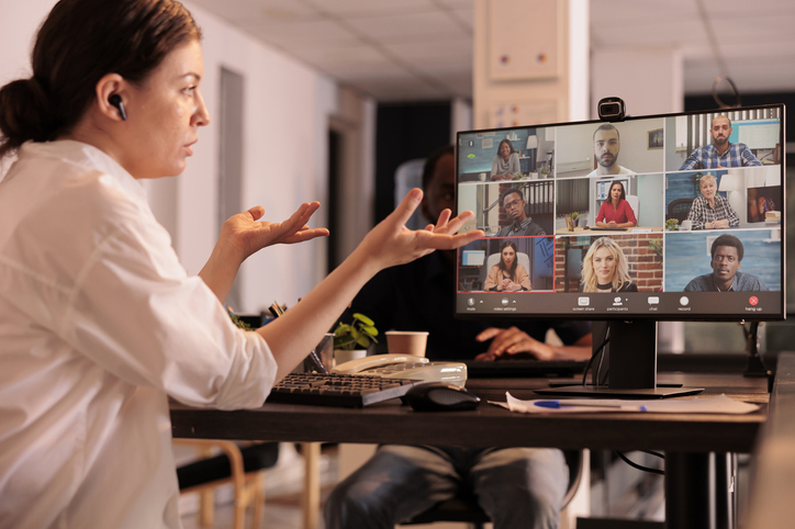 Eine Frau sitzt vorm Computer und spricht zu den Menschen in einem Online Meeting