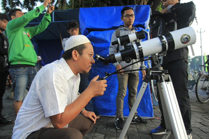 Ein Mann blickt durch ein Teleskop in die Ferne